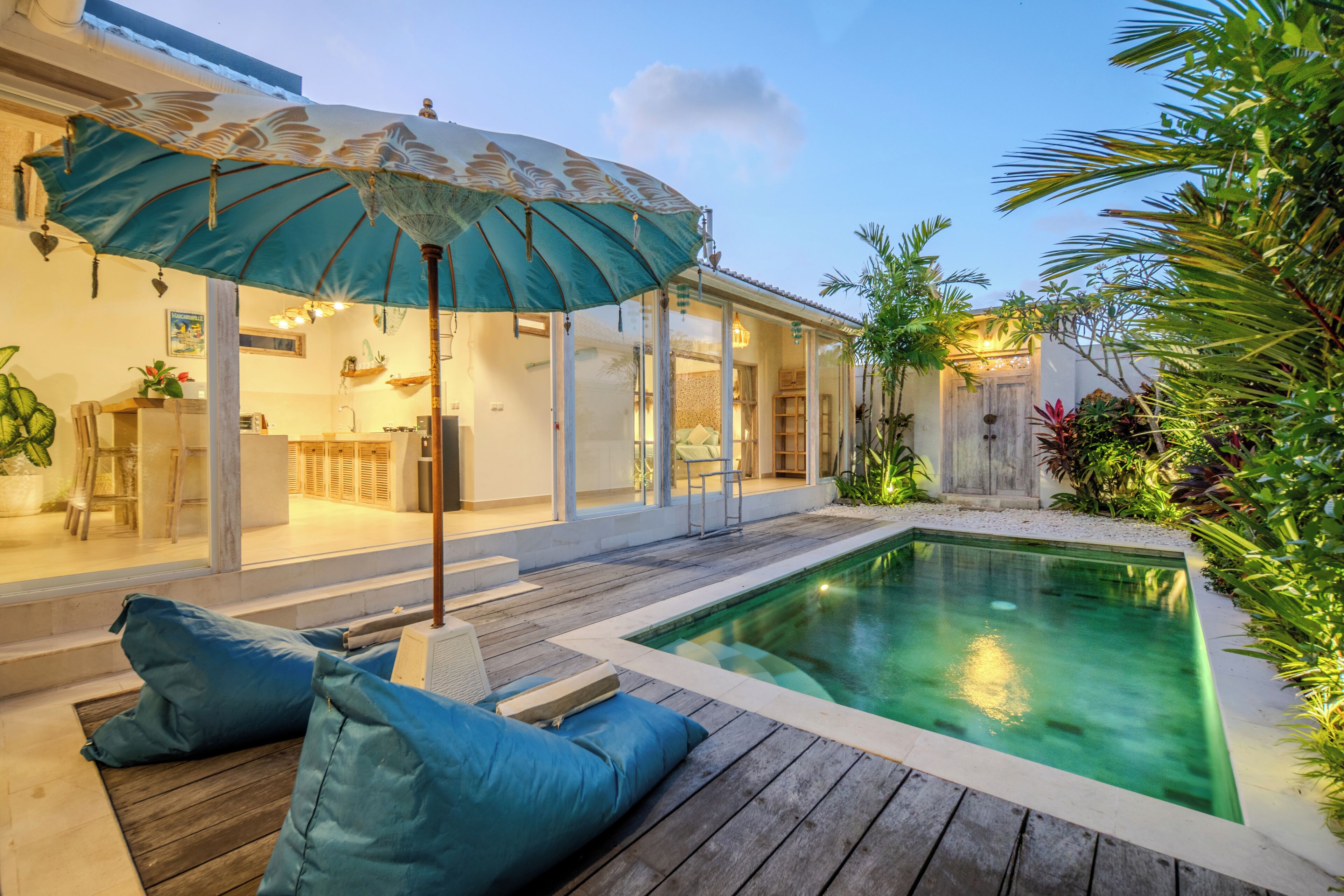 A poolside area with a wooden deck, a lounge chair, and a large umbrella.
