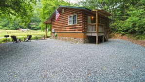 Une cabane en bois avec un porche, un drapeau et une allée gravillonnée.