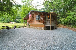 Eine Holzhütte mit Veranda, einer Flagge und einem Schotterweg.