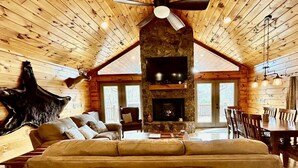 Ein rustikales Holzhaus-Interieur mit Kamin aus Stein, Ledersofa und Essbereich.