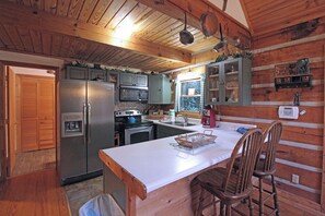 Une cuisine de style rustique, équipée d’un réfrigérateur, d’une cuisinière, d’un four à micro-ondes et de meubles de rangement en bois.