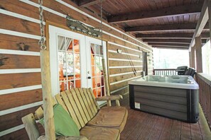 Eine Holzhütte mit Whirlpool, einer Holzbank und einer Tür mit Vorhängen.