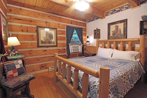 A wooden cabin bedroom with a bed, a chair, a lamp, and a framed picture on the wall. - Tannembaum Hidden Mountain Gem with WIFI (Bryson City)