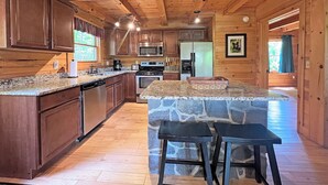 Een houten cabinemakerinterieur met keuken, een keukeneiland van steen en barstoelen.