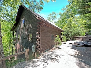 A rustic log cabin with a steep roof, surrounded by trees and a gravel path. - THERZ A BEAR charming log cabin (Bryson City)