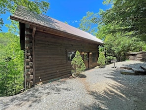 Ein rustikales Holzhaus mit Kiesweg, umgeben von Bäumen.