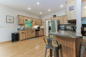 Eine moderne Küche mit Holzschränken, einem Edelstahlkühlschrank und einer Arbeitsplatte aus Granit.