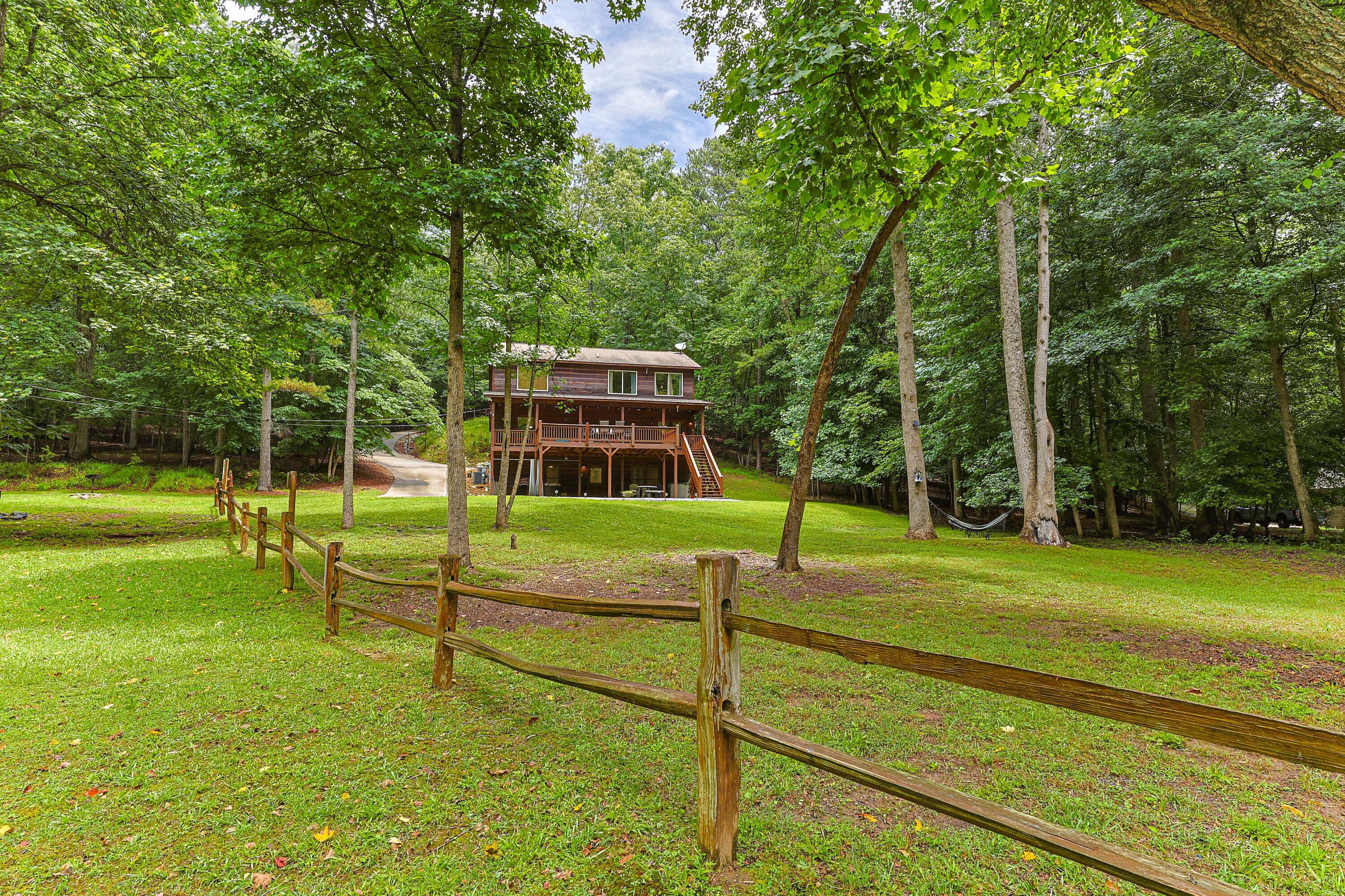 A cabin with a deck, surrounded by a wooden fence and trees.
