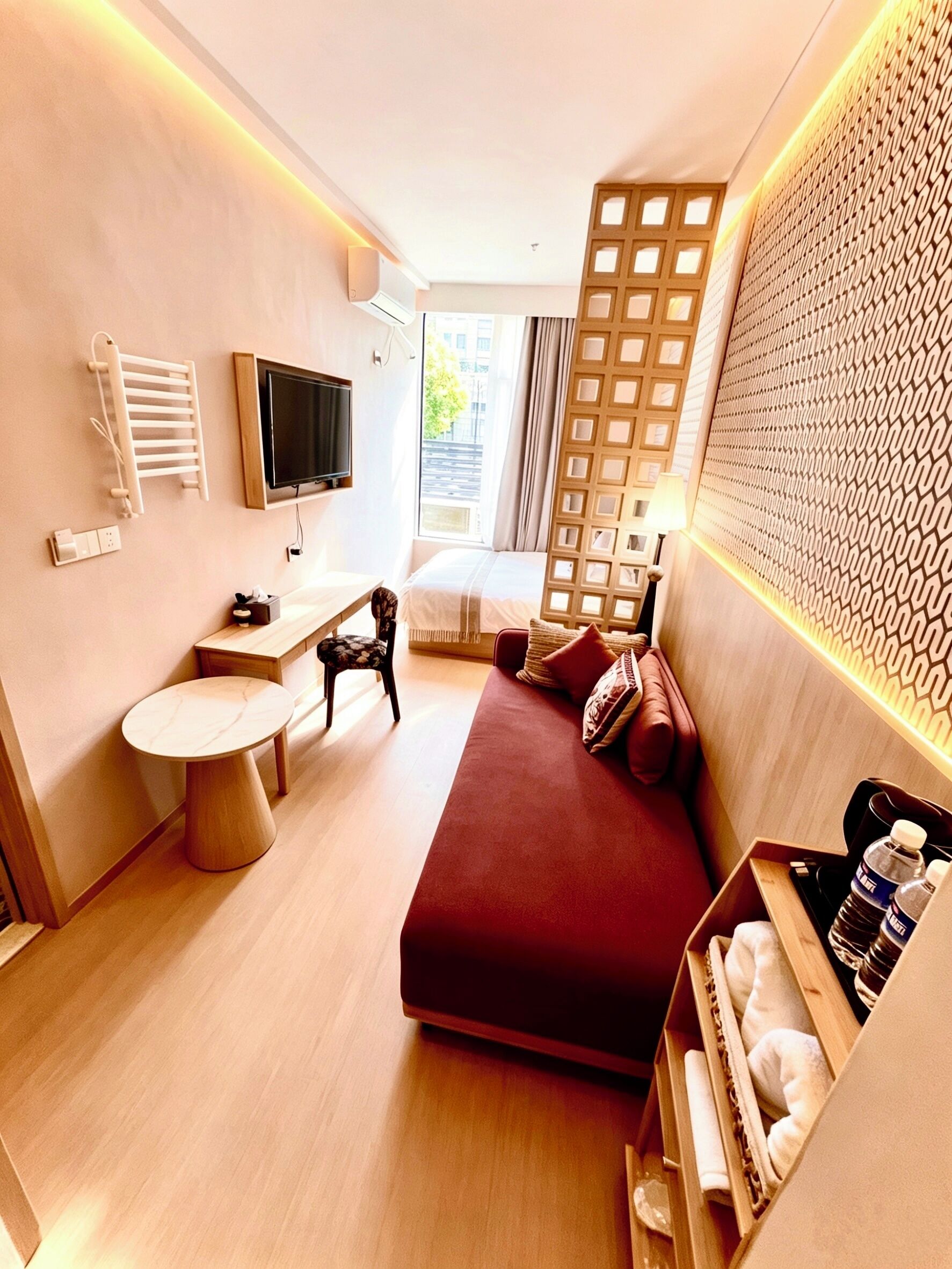 Habitación de hotel moderna con cama, mesita de noche, silla, televisor y vistas al exterior.