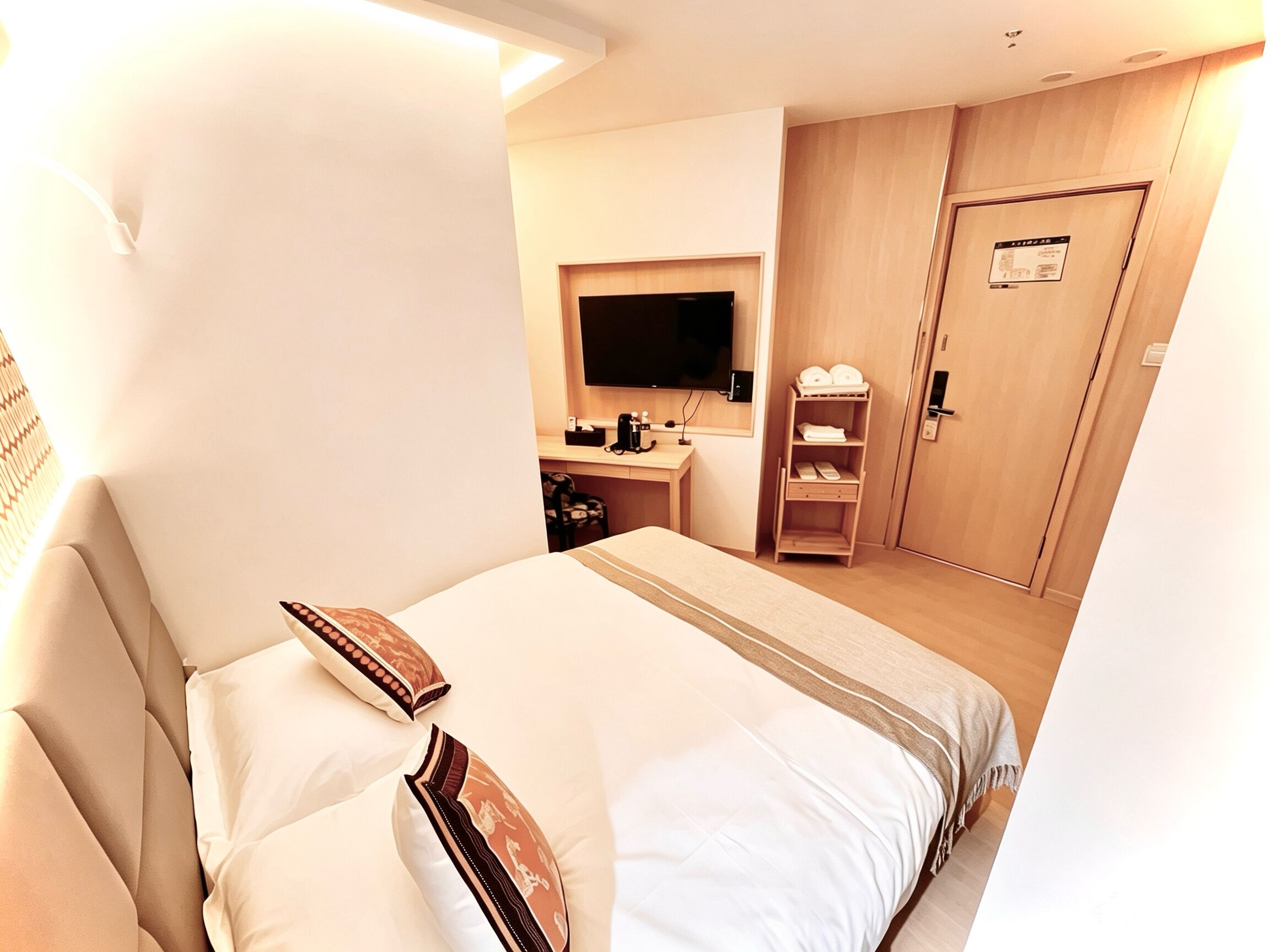 A hotel room with a bed, a desk, a television, and a wardrobe.