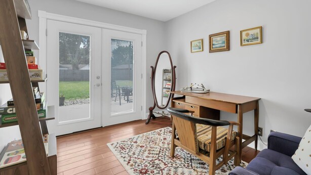 A room with a wooden desk, a chair, a mirror, and a blue sofa. There are three framed pictures on the wall.
