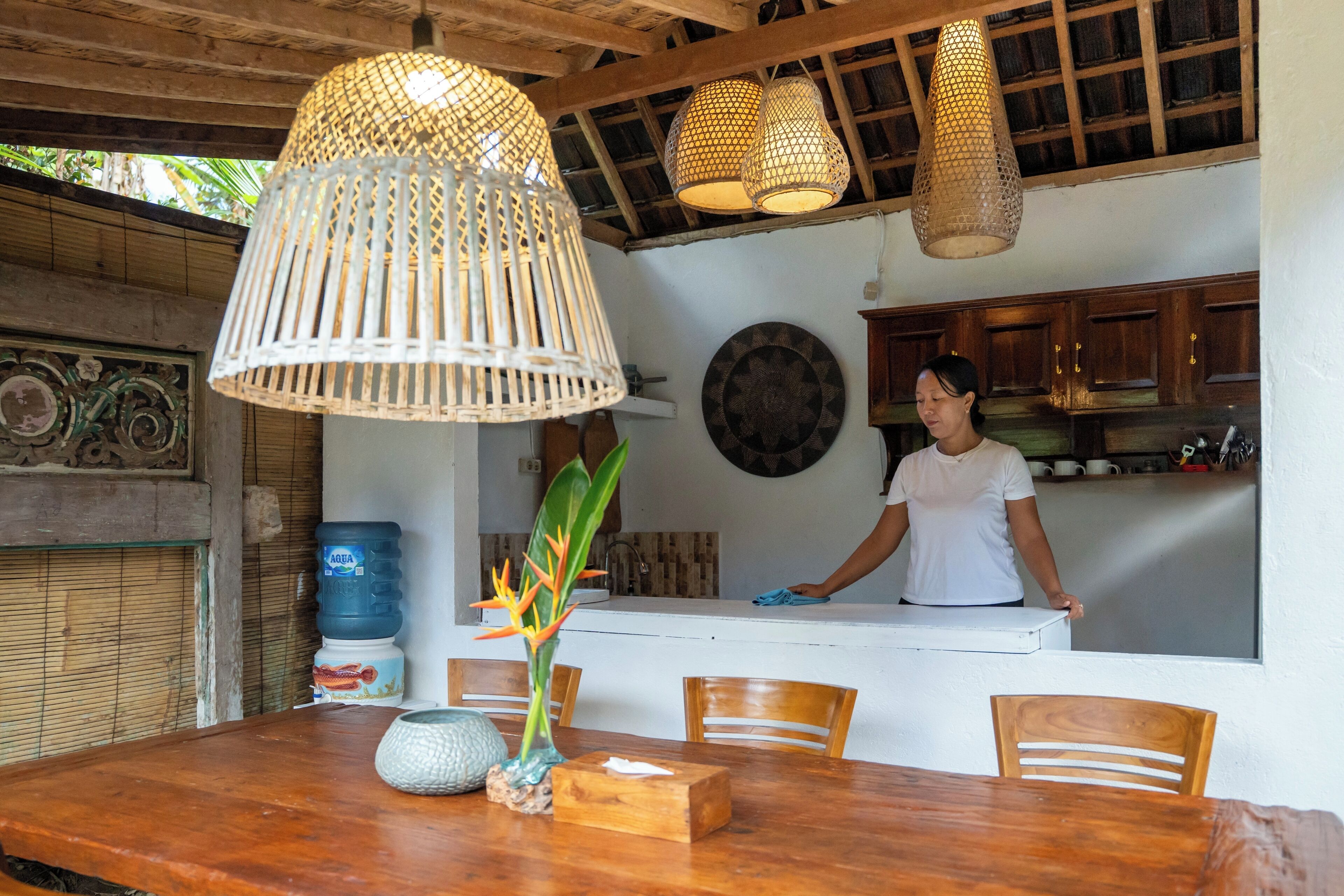 A kitchen with wooden cabinets, a water dispenser, a decorative plate, and a hanging light fixture.