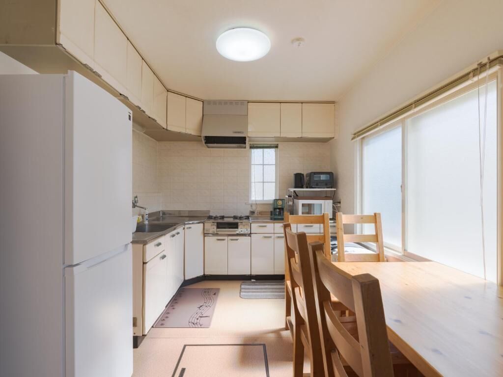 A compact kitchen with white cabinets, a microwave, a stove, and a dining area with a wooden table and chairs.