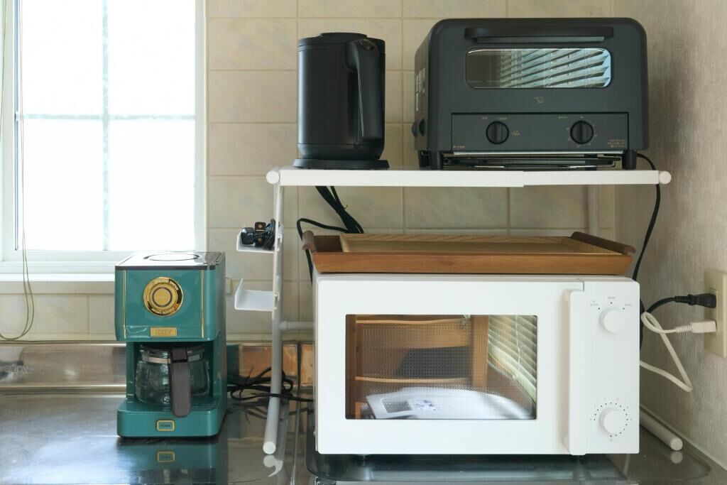 Una cocina con cafetera, tostadora y microondas en un estante.