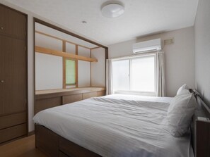 A bedroom with a bed, a wardrobe, a window with curtains, and an air conditioning unit. - Slow Toya (Abuta-gun Toyako-cho)