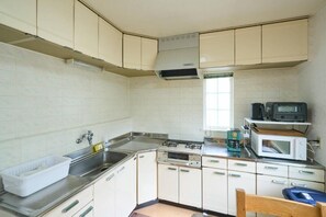 A kitchen with white cabinets, a stainless steel sink, a microwave, and a coffee maker.