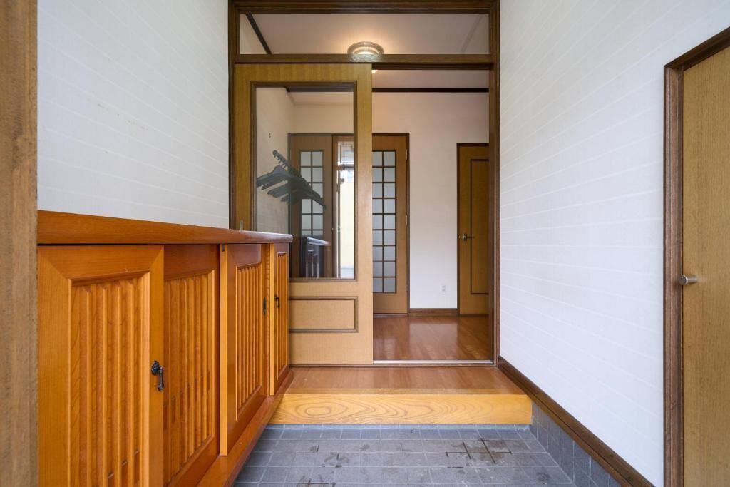 Un pasillo con puertas de madera, suelo de baldosas y un banco de madera.
