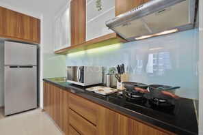 A modern kitchen with a stainless steel refrigerator, a microwave, and a gas stove. - Astera by Kozystay - Kuningan (South Jakarta)
