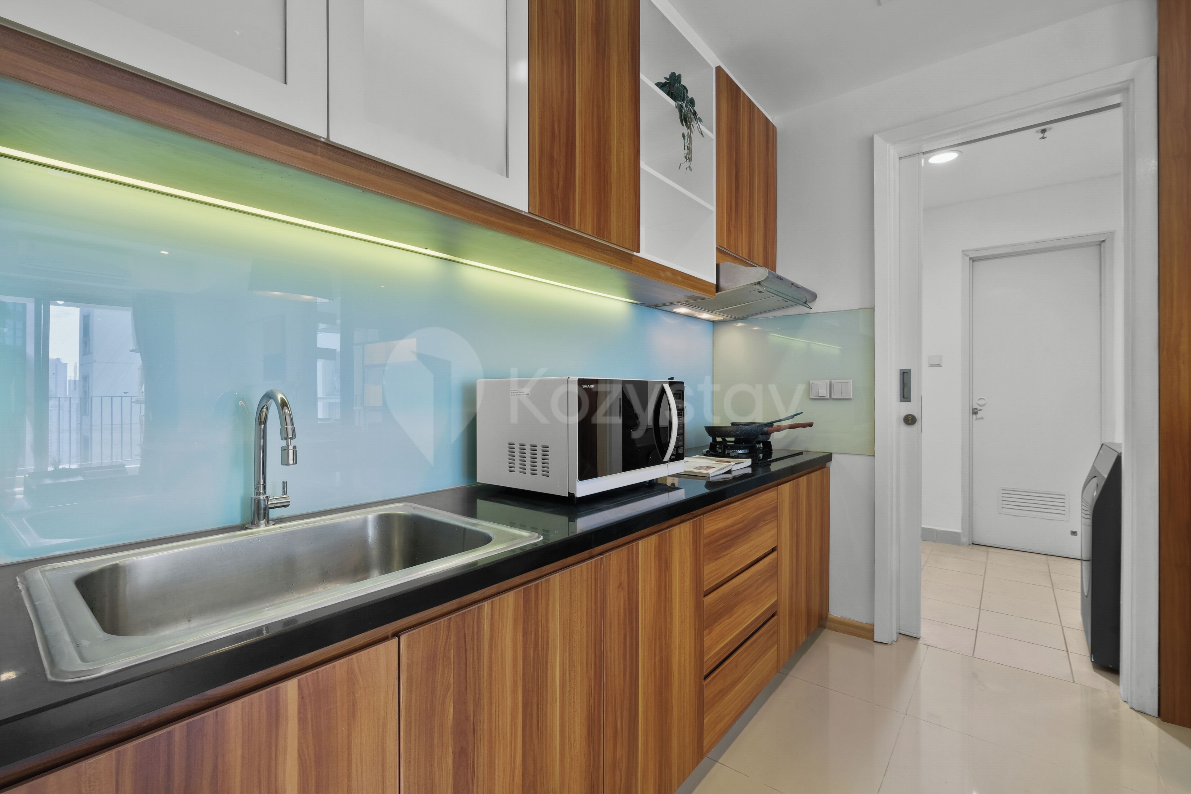 A modern kitchen with a stainless steel sink, wooden cabinets, a microwave, and a stove.
