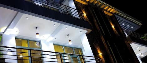 Un edificio de varios pisos con balcones, ventanas amplias e iluminación exterior.