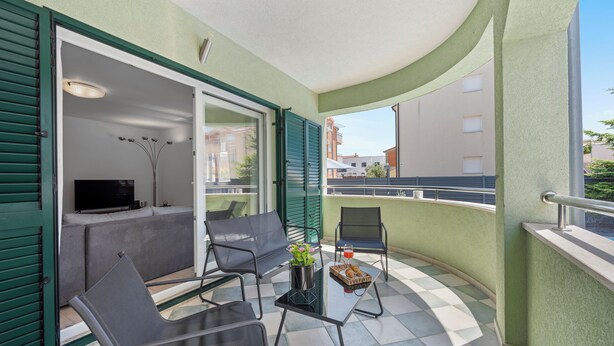 A balcony with a seating area, a table with a drink and pastries, and a TV in the background. - S Villa with Pool, Jacuzzi & Gym, Šibenik, Croatia (Šibenik)