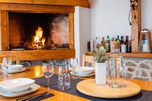 A dining area with a fireplace, a table set with plates, glasses, and cutlery, and a shelf with various bottles. - S Villa with Pool, Jacuzzi & Gym, Šibenik, Croatia (Šibenik)