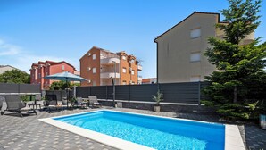 A rectangular swimming pool with a tiled deck, surrounded by lounge chairs and a potted plant. - S Villa with Pool, Jacuzzi & Gym, Šibenik, Croatia (Šibenik)