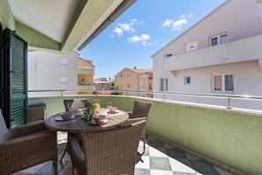 A balcony with wicker furniture, a table set for two, and a view of neighboring buildings. - S Villa with Pool, Jacuzzi & Gym, Šibenik, Croatia (Šibenik)
