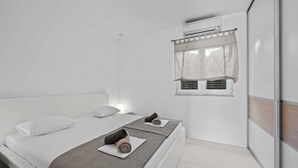 A modern bedroom with two beds, a window with a curtain, and an air conditioning unit. - S Villa with Pool, Jacuzzi & Gym, Šibenik, Croatia (Šibenik)