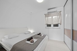 Ein modernes Schlafzimmer mit zwei Betten, einem Fenster mit Vorhang und einer Klimaanlage.