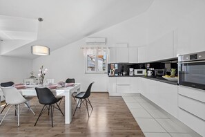 A modern kitchen with white cabinetry, a dining table with chairs, and a hanging light fixture. - S Villa with Pool, Jacuzzi & Gym, Šibenik, Croatia (Šibenik)