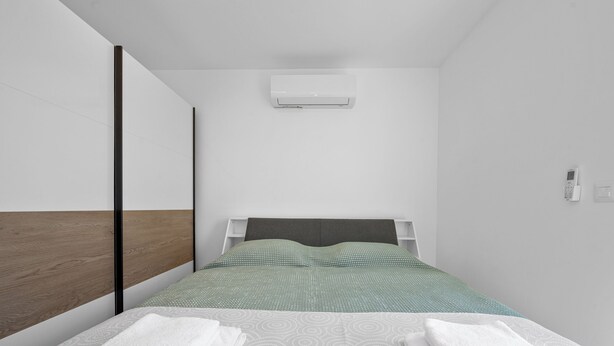 Een moderne hotelkamer met een bed, een wandairconditioner en een bedtafeltelefoon.