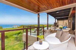 Ein Balkon mit Meerblick, ein weißes Sofa und ein kleiner Tisch mit einer Pflanze.