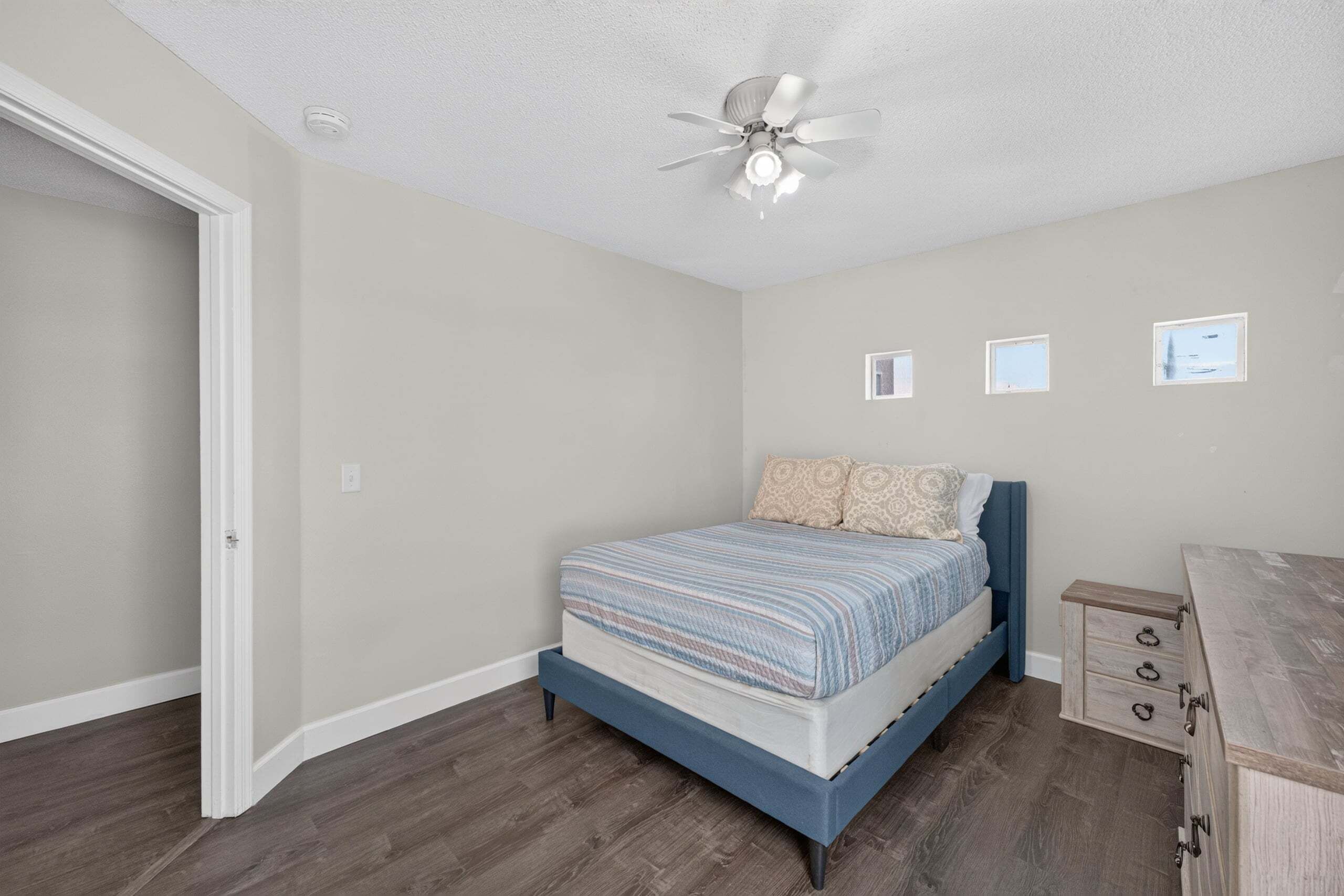 A bedroom with a bed, a ceiling fan, and a small window.