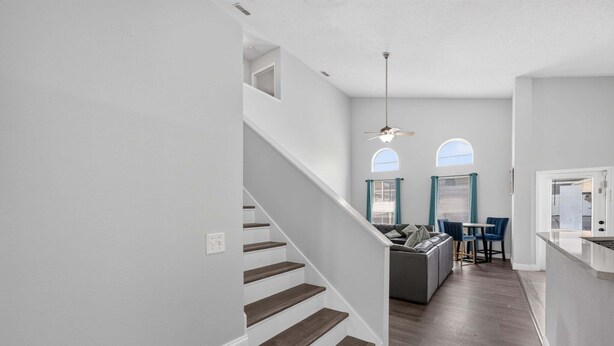 A modern interior with a staircase, a dining area, and a kitchen. - Spacious 5BR Pool Home Near Disney (Davenport)