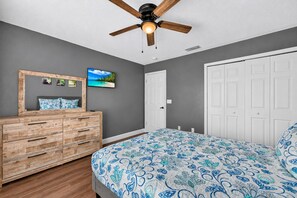A bedroom with a bed, wooden dresser, ceiling fan, and a door. - Spacious 5BR Pool Home Near Disney (Davenport)