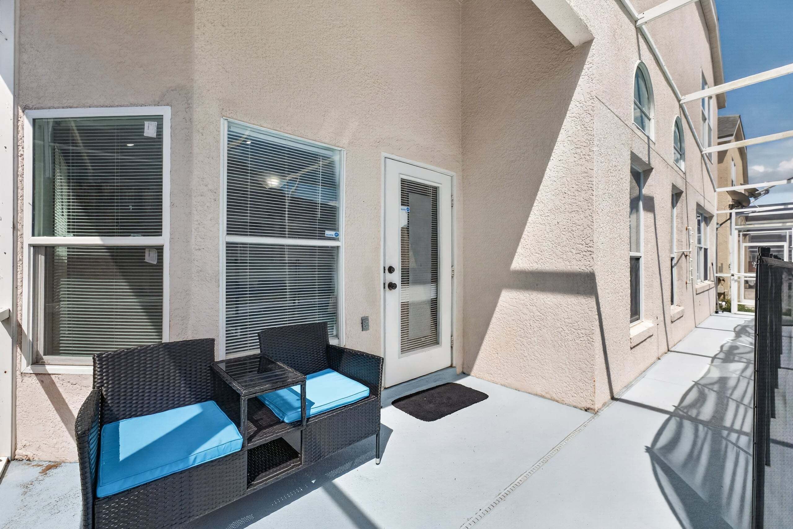 A building with a covered outdoor seating area, a door, and windows with blinds.