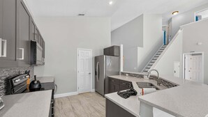 A modern kitchen with grey cabinets, a stainless steel refrigerator, and a built-in oven. - Spacious 5BR Pool Home Near Disney (Davenport)