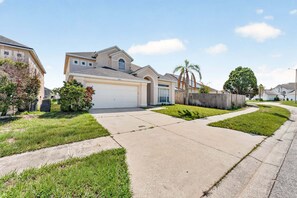 A suburban neighborhood with single-family homes, a paved driveway, and well-maintained lawns. - Golden Light Retreat | 5BR Davenport w/ Pool (Davenport)