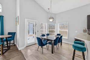 A dining area with a table and chairs, a kitchen area with a counter, and a ceiling light fixture. - Golden Light Retreat | 5BR Davenport w/ Pool (Davenport)