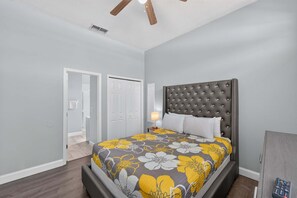 Ein Schlafzimmer mit einem Bett, einem Nachttisch, einer Lampe und einem Deckenventilator.