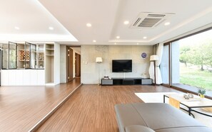 Una sala de estar moderna con una televisión de pantalla plana, un sofá, una mesa de centro y un amplio ventanal con vistas al exterior.