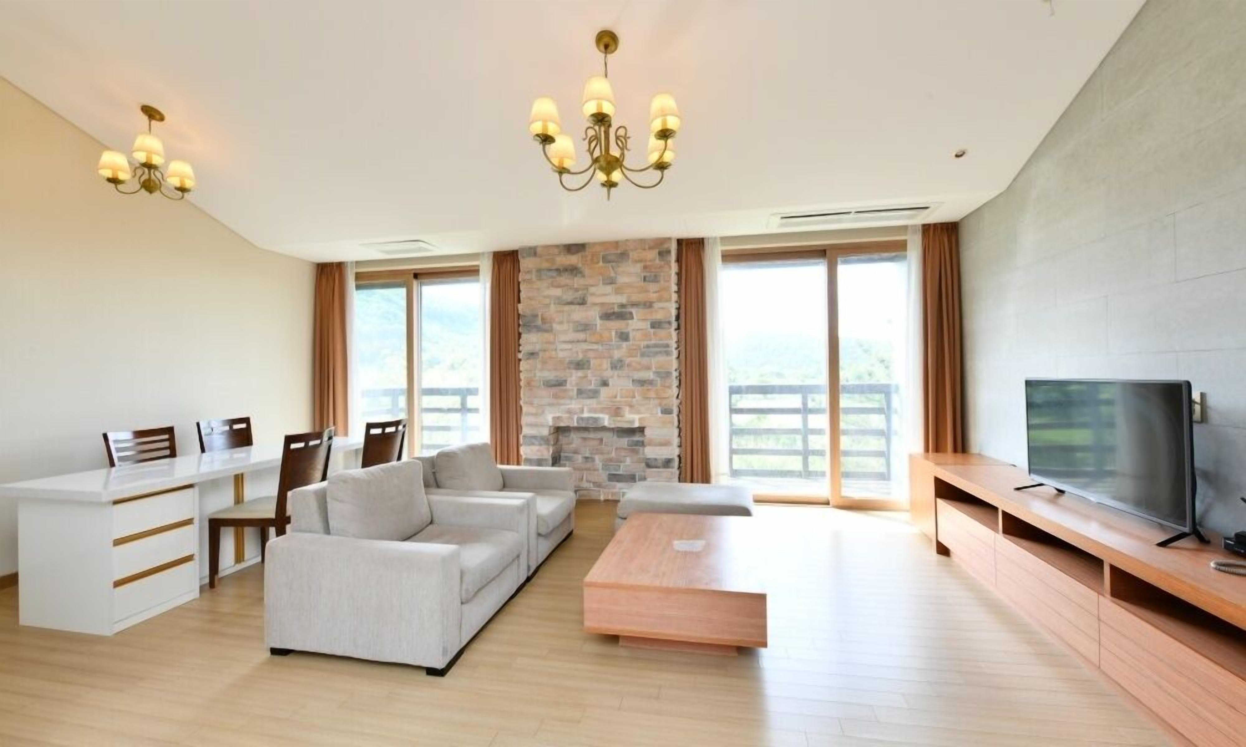 A modern living room with a fireplace, a sofa set, a coffee table, and a television on a wooden stand.