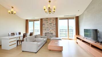 A modern living room with a fireplace, a sofa set, a coffee table, and a television on a wooden stand.