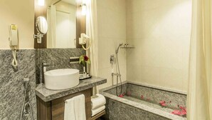 Ein Badezimmer mit Marmorwaschbecken, Spiegel, Dusche und Handtuchhalter.