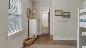 A hallway with a white wall, a wicker basket, a white lamp, and a door leading to another room. - Boho-Chic House Near 30A Beach w/ Pool & Hot Tub (Santa Rosa Beach)