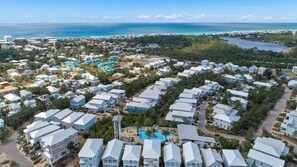 A coastal residential area with multiple-story houses, a central swimming pool, and a view of the ocean. - Boho-Chic House Near 30A Beach w/ Pool & Hot Tub (Santa Rosa Beach)