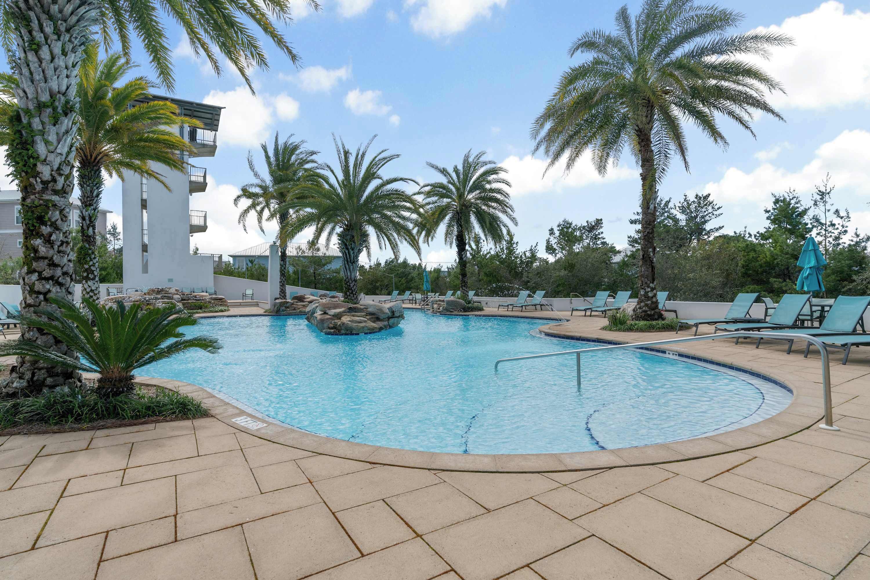 Una piscina con lettini e palme.