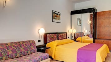 Quarto de hotel com cama, sofá, mesa de cabeceira e espelho.