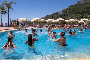 Een zwembad met mensen die van het water genieten, omringd door parasols en stoelen.